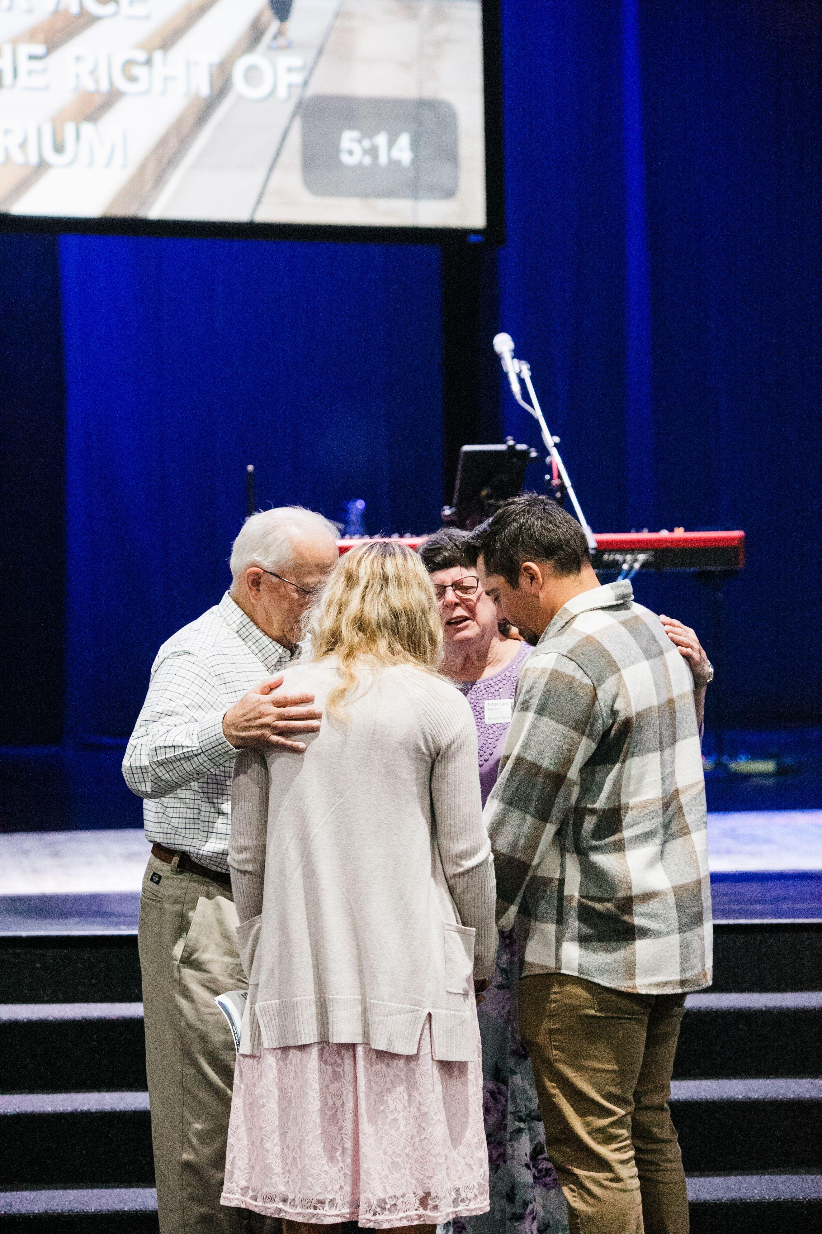 adults praying together at church.