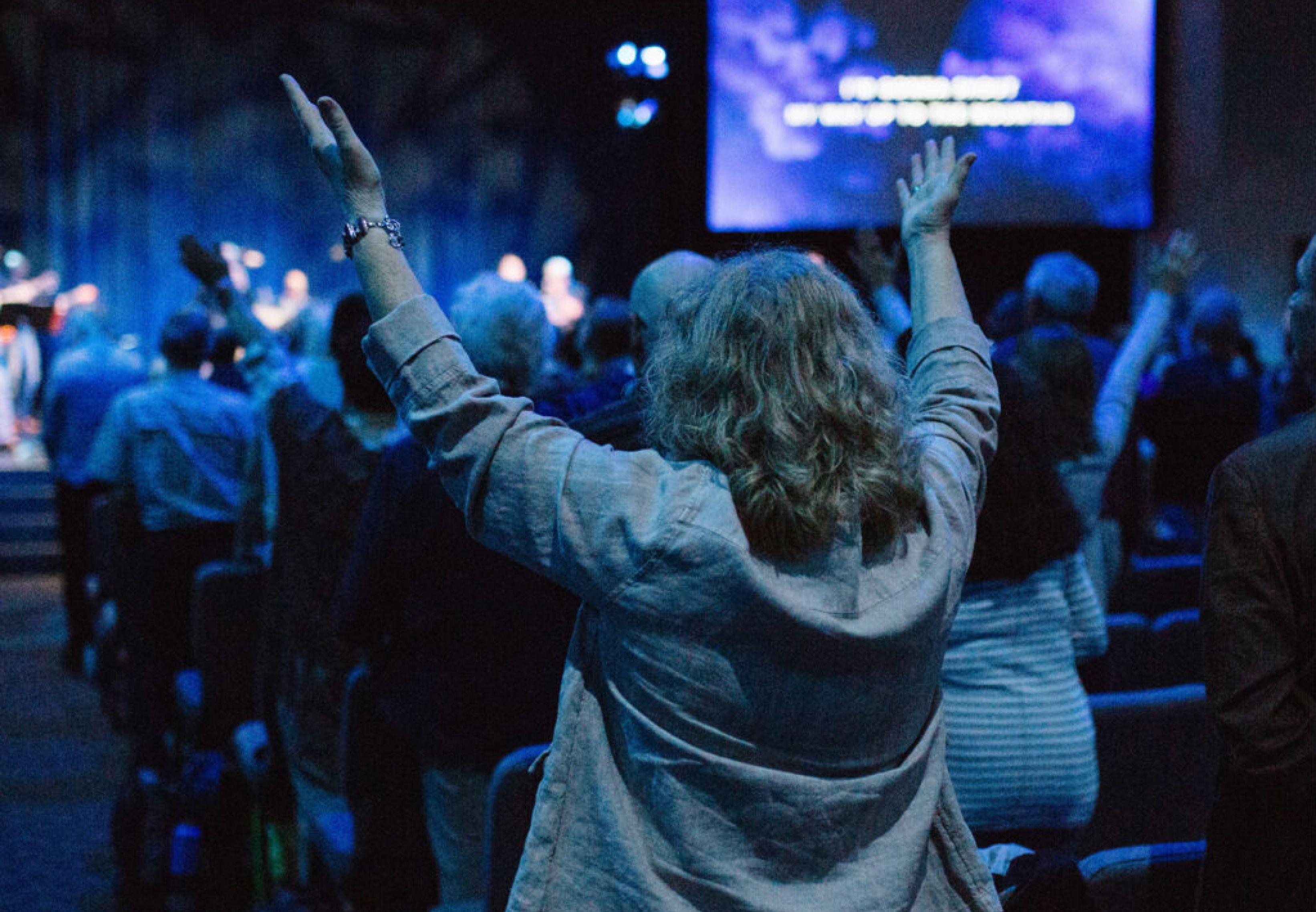 woman raising her hands in worship at church.